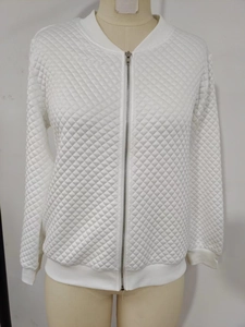 Detail of white quilted bomber jacket showing textured diamond pattern and silver zipper