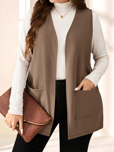 Detail of long brown sleeveless blazer vest with large utility pockets and draped fit