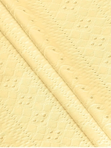 Makroaufnahme von hellgelbem Lochstickerei-Stoff mit geometrischer Diamant-Stickerei