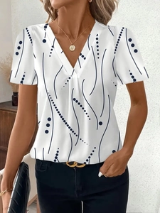 Dettaglio della camicetta in chiffon bianco con scollo a V e pois astratti blu navy