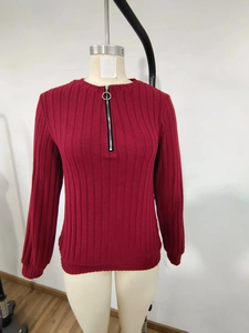 Detail view of red ribbed knit top featuring a round neck and silver half-zip design