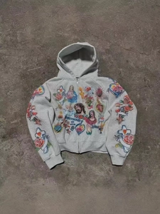 Detailed close-up of religious art prints on a grey zip-up hoodie with vintage tattoo patterns