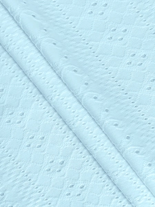 Nahaufnahme von hellblauem Spitzenstoff mit filigranen Blumenmustern und weicher Textur