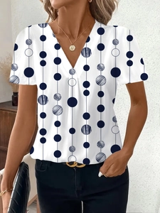 Dettaglio dello scollo a V e della stampa geometrica a pois blu navy sul top bianco