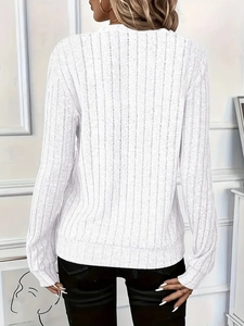Detail shot of white long-sleeve knit top featuring vertical ribbed texture and elastic cuffs