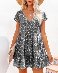Detail of V-neck floral summer dress with button front and pleated layered skirt