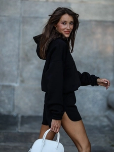 Detail of black long-sleeve hoodie with side-slit shorts and a minimalist handbag