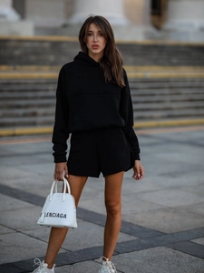 Close-up of minimalist black long-sleeve hoodie and shorts set in urban streetwear style