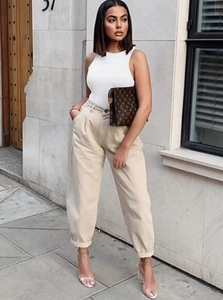 Close-up of white ribbed sleeveless tank top paired with beige high-waisted pleated trousers