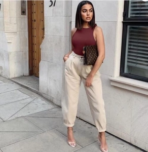 Street style shot of a burgundy sleeveless bodysuit paired with beige high-waist trousers