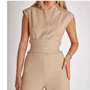 Tuta beige senza maniche con collo alto e gamba larga con cintura per un look snello