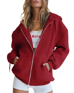 Detail of red oversized hoodie featuring silver metal zipper and soft fleece fabric