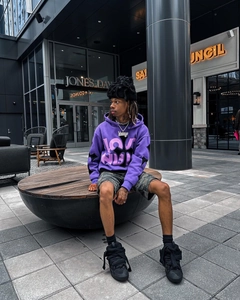 Street style shot of oversized purple hoodie with cross graphic and heavy cotton texture