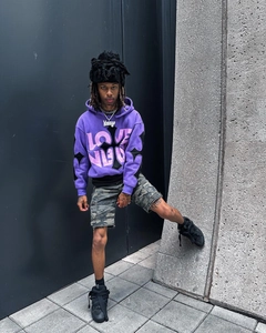 Detail of oversized purple hoodie featuring pink LOVE text and black cross graphic design