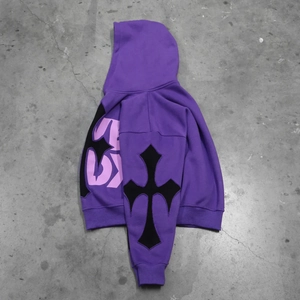 Detail of purple oversized hoodie featuring black cross patch and graphic sleeve prints