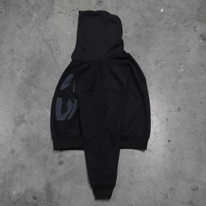 Detailed view of grey lettering and cross patterns on the sleeve of a black hoodie