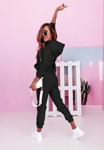 Detail eines schwarzen Kapuzenpullovers und Joggingshosen-Sets auf schickem rosa Hintergrund