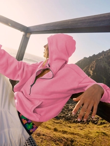 Detail of bright pink hooded sweatshirt with quarter zipper and drawstrings in sunlight