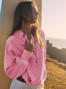 Detail of pink half-zip hoodie with ribbed cuffs and pocket by the seaside sunset