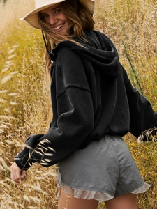 Close-up of a oversized black zip-up hoodie with washed texture in an outdoor setting