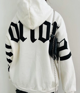 Detail view of gothic black lettering print on the back of a white oversized hoodie