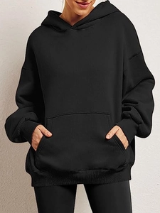 Detail of oversized black hoodie featuring a kangaroo pocket and ribbed cuffs in soft knit