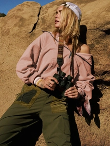 Detail of pink half-zip hoodie with ribbed cuffs and utility pockets shown outdoors