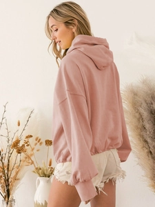 Detail of oversized pink hoodie with drawstring hem and soft cotton fabric texture