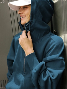 Detail of teal half-zip hoodie with dropped shoulders and heavy knit texture