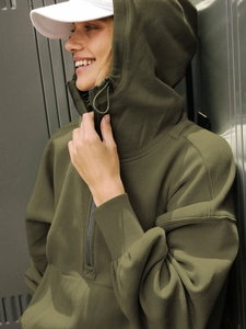 Detail of dark green hoodie featuring half-zip high neck and ribbed cuffs for cozy style