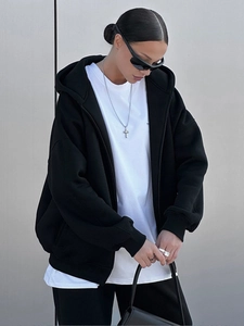 Detail eines schwarzen Oversize-Kapuzenpullis mit Reißverschluss und überschnittenen Schultern