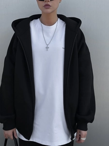Detail eines schwarzen Oversize-Kapuzenpullovers mit weißem T-Shirt und Silberkreuzkette