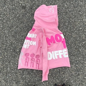 Detail of pink hoodie with street style graffiti print and raw cut hem on asphalt