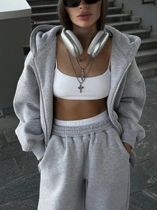 Detail von grauem Oversized-Zip-Hoodie und Jogginghose auf Steintreppen im Freien