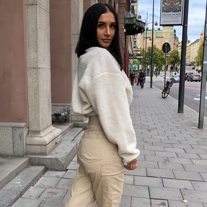 Street style shot of white plush fleece zip-up jacket and beige cargo trousers
