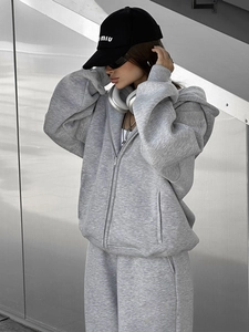 Detail eines grauen Kapuzenpullovers mit Reißverschluss und passender Jogginghose für Damen