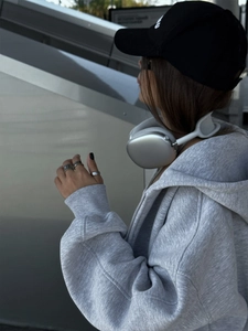 Detail eines grauen Oversized-Kapuzenpullovers mit Reißverschluss in moderner Optik