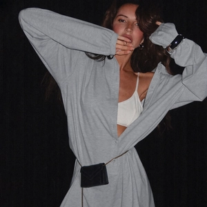 Detail of light gray long sleeve buttoned romper with a black chain mini waist bag