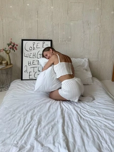 Detail of white ribbed knit loungewear set featuring crop tank top and ruffle hem shorts