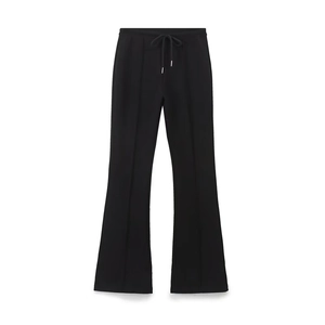 Dettaglio dei pantaloni svasati neri in maglia con coulisse elastica e cuciture medie