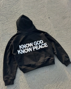 Close-up of 'KNOW GOD KNOW PEACE' white lettering on a black cotton streetwear hoodie