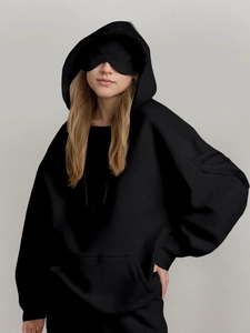 Detail view of black oversized hoodie with large pocket, sleeve zipper, and matching eye mask