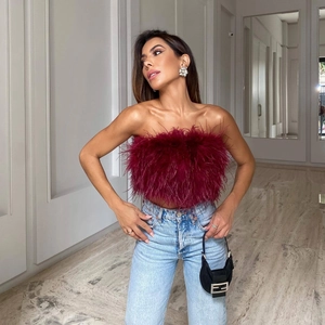 Elegante top a fascia in piume rosso vino abbinato a jeans blu chiaro per un look chic