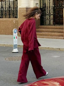 Street view of a woman wearing a wine red linen two-piece set with shirt and wide trousers