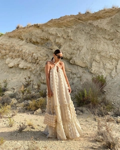 Detail of cream multi-layered halter dress featuring textured floral fabric and tiered hem