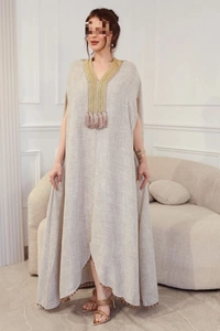 Détail du décolleté en V avec broderie dorée et pompon sur robe kaftan en lin