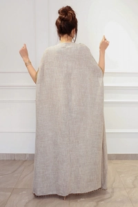 Détail du cardigan en lin avec paillettes aux manches et ourlet décoré de petits pompons