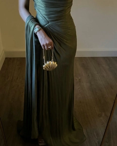 Detail of pleated olive green evening dress with a golden shell-shaped clutch bag