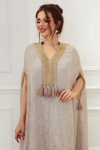 Détail de broderie sur col en V et glands en soie sur une robe caftan en lin