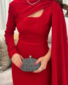 Detailopname van elegante rode avondjurk met één schouder, lange cape en strass-clutch